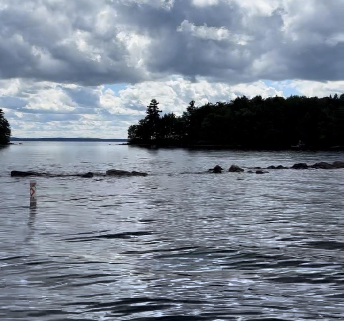 Exposed rocks and a navigation marker on Sebago Lake during low summer water levels