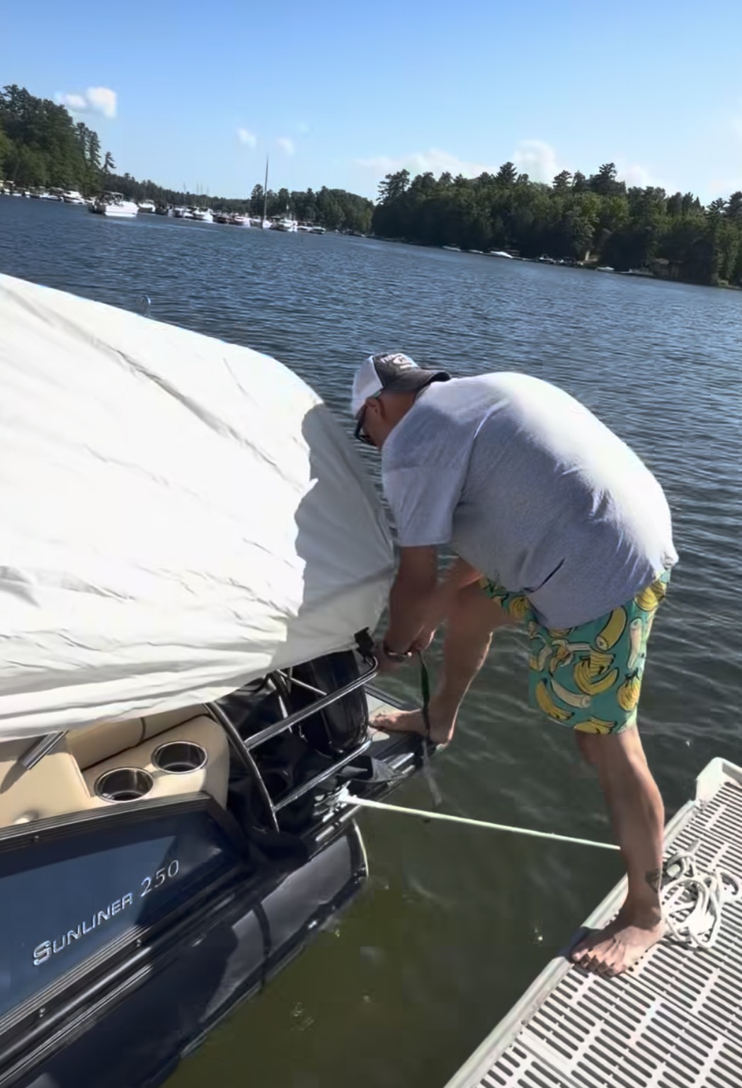 Boater fastening a lightweight white pontoon cover at the bow
